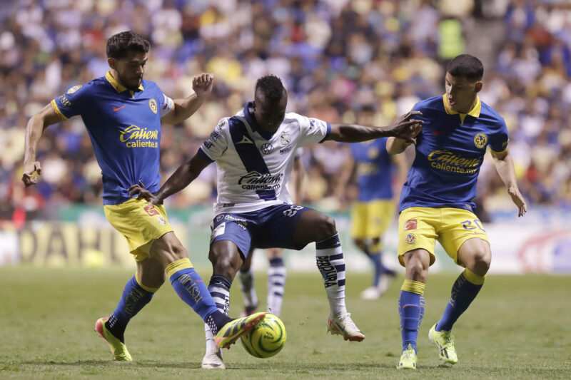 El lateral izquierdo colombiano Kevin Velasco (c), de Puebla, disputa el balón con los jugadores de América Henry Martín (i) y Richard Sánchez (d) este viernes, durante un partido de la jornada 17 del torneo Clausura mexicano jugado en el estadio Cuauhtémoc. EFE/Hilda Ríos