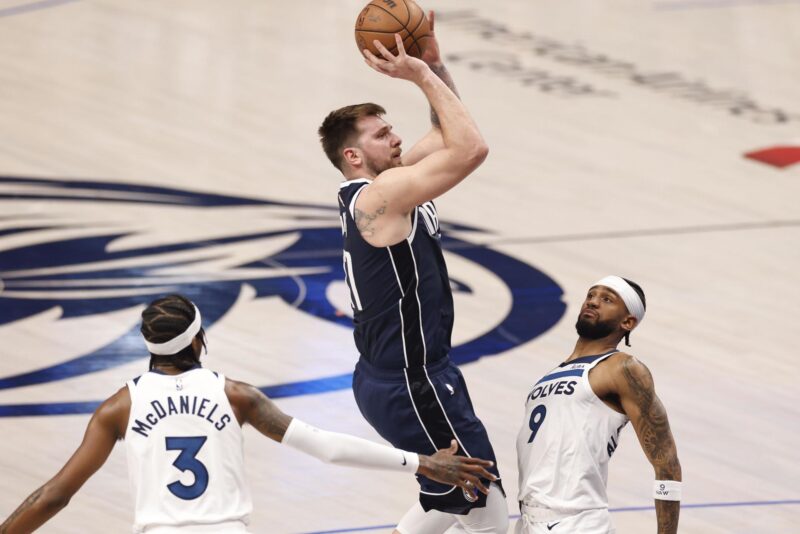 Luka Doncic (c) de los Dallas Mavericks lanza con la marca de Jaden McDaniels (i) y Nickeil Alexander-Walker (d) de los Minnesota Timberwolves durante un juego de la NBA. EFE/EPA/ADAM DAVIS