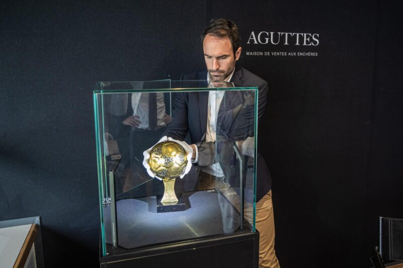 Francois Thierry, experto en deportes de la casa de subastas Aguttes, instala en la vitrina el el Balón de Oro que ganó Diego Maradona en el Mundial de México 1986 y que se podrá subastar tras dar luz verde un tribunal de Nanterre, a las afueras de París. EFE/EPA/CHRISTOPHE PETIT TESSON