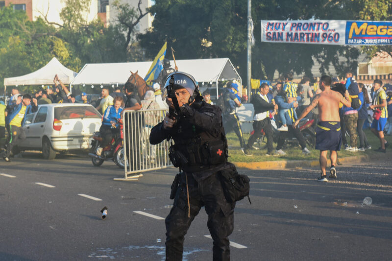 Un agente de la policía argentina intimida con su arma a fanáticos del club Rosario Central que salieron a los alrededores del estadio Gigantes de Arroyito para saludar a sus jugadores antes del partido de Copa Libertadores jugado a puerta cerrada que ganó Atlético Mineiro por 0-1. EFE/ Franco Trovato Fuocoo