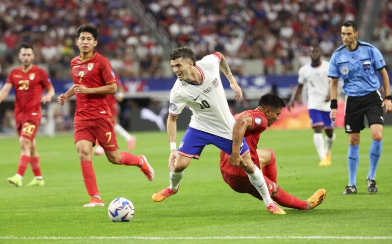 El delantero estadounidense Christian Pulisic (C) y el centrocampista boliviano Héctor Cuellar (d) en la Copa América 2024. (Estados Unidos) EFE/EPA/KEVIN JAIRAJ