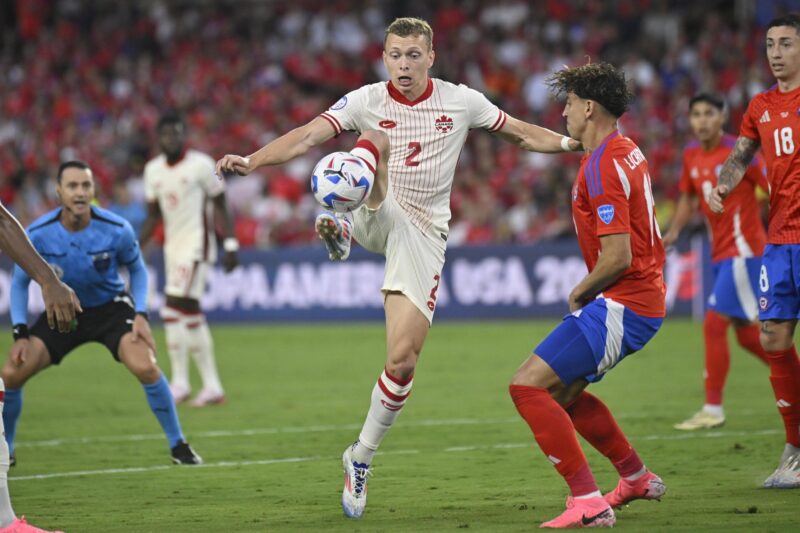 El defensa canadiense Alistair Johnston (c) fue registrado este sábado, 29 de junio, al disputar un balón con el defensa chileno Igor Lichnovsky (3-d), durante el partido de cierre del grupo A de la Copa América 2024, en el estadio Inter&Co de Orlando (Florida, EE.UU.). Canadá empató 0-0 con Chile y avanzó, en su debut en el torneo, a los cuartos de final. EFE/Miguel Rodríguez